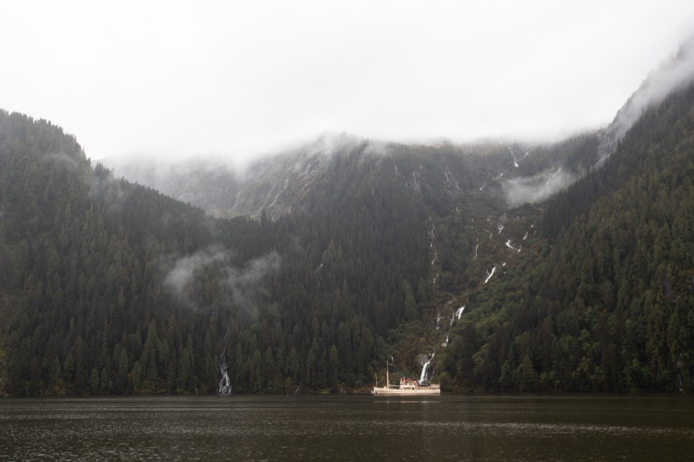 A boat at anchor under the falls in fog, British Columbia, Canada