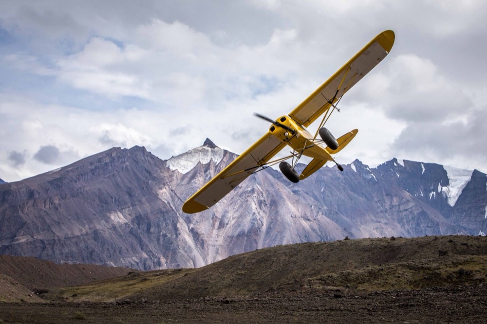 A bush plane climbing off a gravel strip