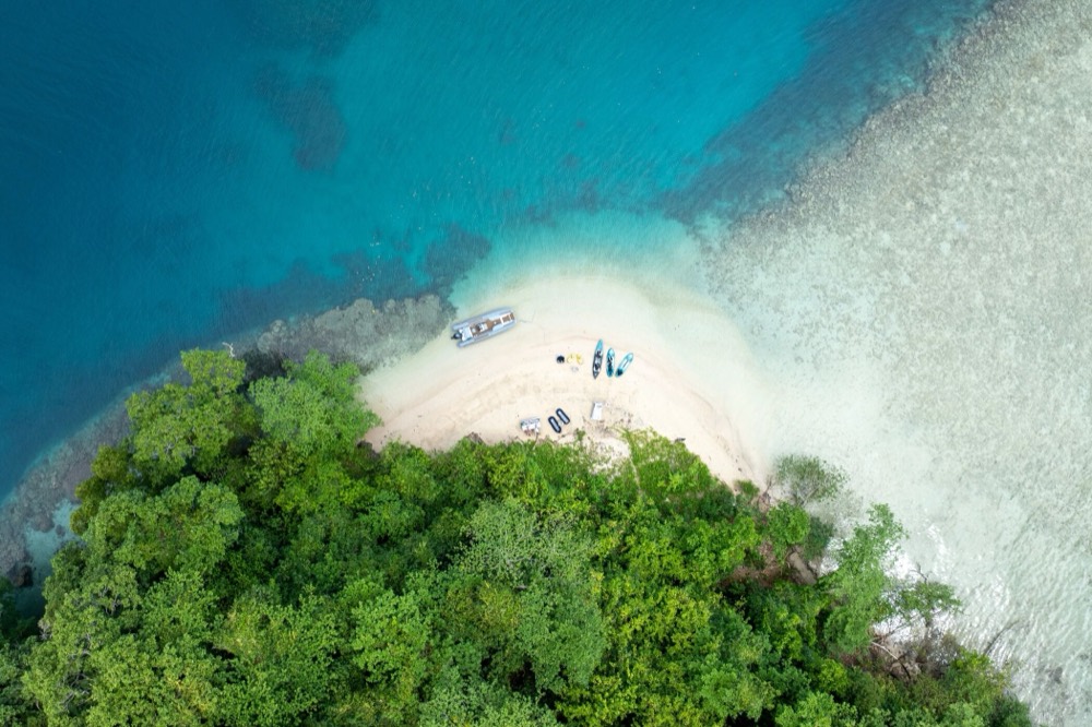 Kayaks and a tender on a reef-fringed spit, Papua New Guinea